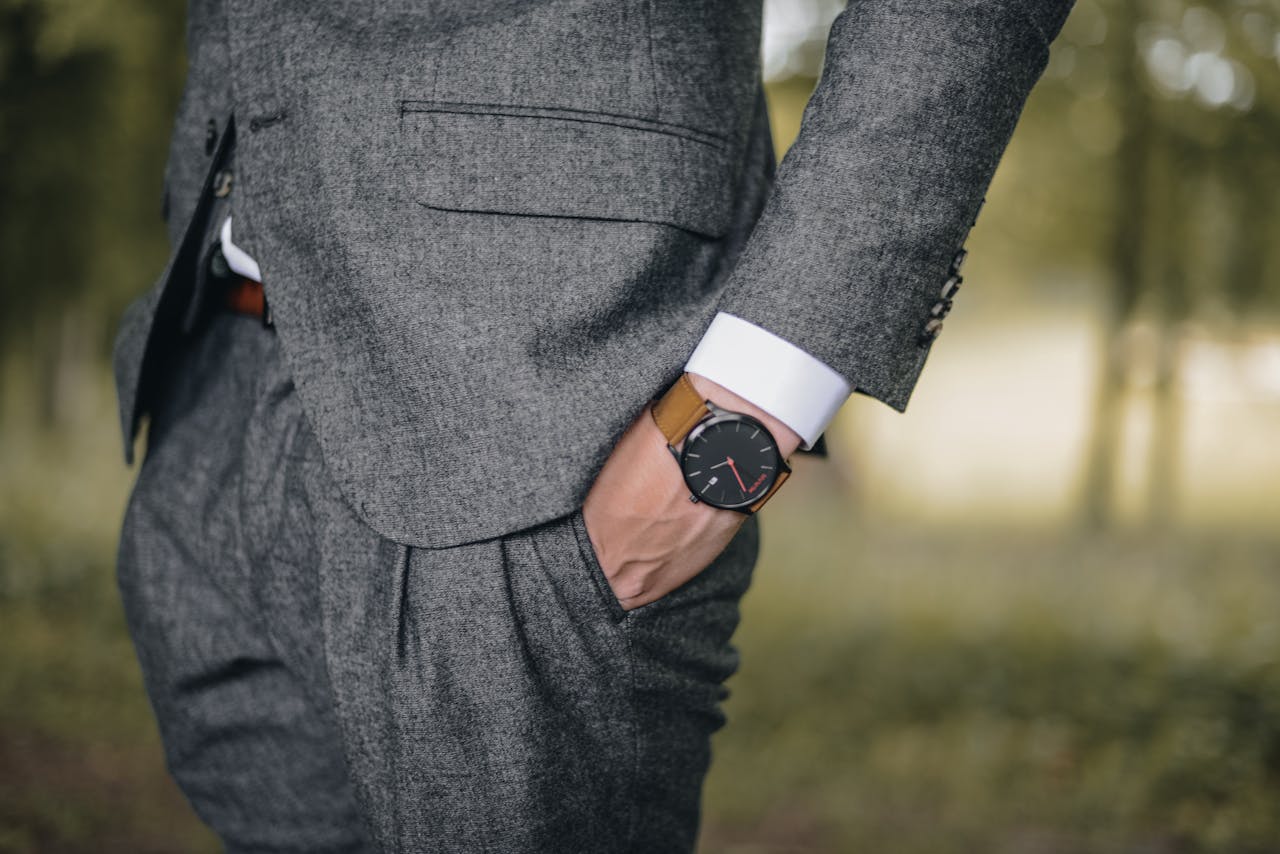 about-us-02 Close-up of a man in a tailored suit wearing an elegant wristwatch outdoors, exuding fashion and sophistication.