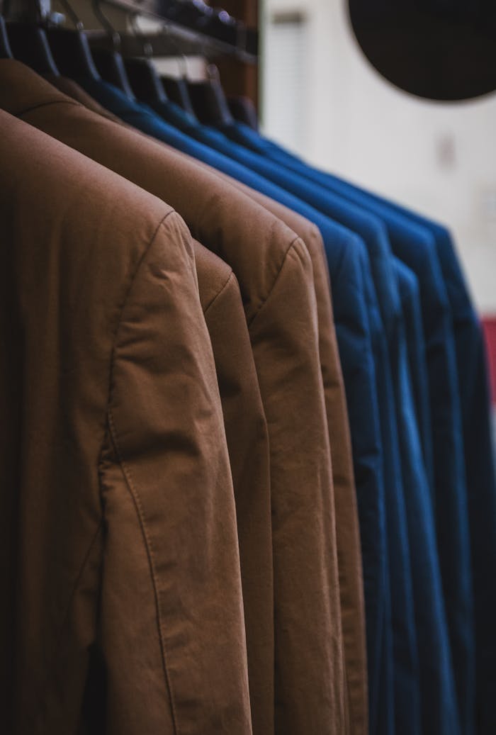 about-us-01 Showcase of neatly arranged brown and blue jackets on hangers, emphasizing fashion and style.